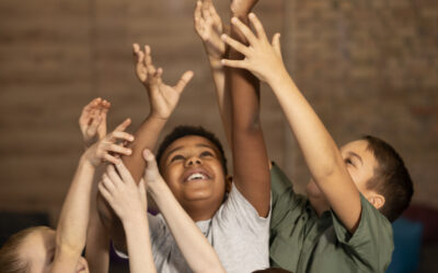 Happy Kids Boutique kinderen met verschillende achtergronden spelen samen met een bal en reiken omhoog, beeld van diversiteit en verschillende culturen waarin samenspel en duurzaamheid centraal staan