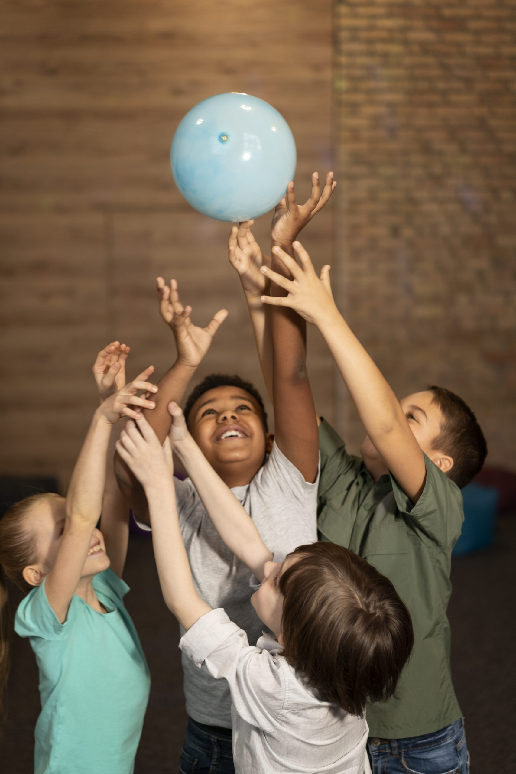 Happy Kids Boutique kinderen met verschillende achtergronden spelen samen met een bal en reiken omhoog, beeld van diversiteit en verschillende culturen waarin samenspel en duurzaamheid centraal staan