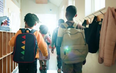 Kinderen lopen met rugzakken door de gang van een basisschool richting het klaslokaal, een dagelijks schoolmoment dat past bij Happy Kids Boutique waar babykleding en babybenodigdheden bijdragen aan comfort, ontwikkeling en duurzaamheid.