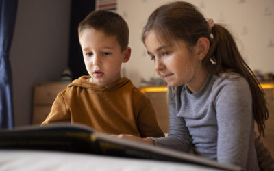Happy Kids Boutique beeld van twee kinderen die samen in een boek kijken en geconcentreerd naast elkaar zitten, een moment waarin kinderen leren omgaan met ruzie en samenwerken met aandacht voor duurzaamheid en ontwikkeling.