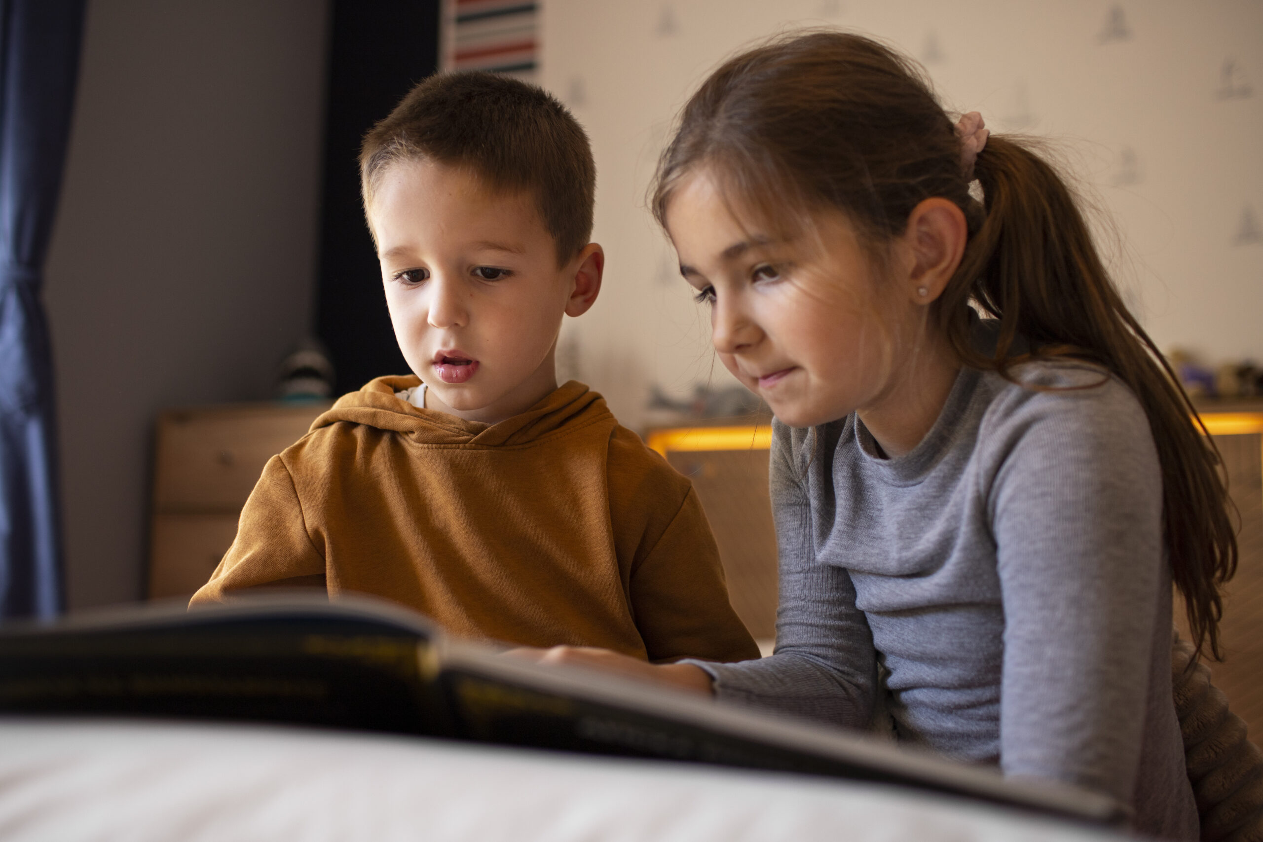 Happy Kids Boutique beeld van twee kinderen die samen in een boek kijken en geconcentreerd naast elkaar zitten, een moment waarin kinderen leren omgaan met ruzie en samenwerken met aandacht voor duurzaamheid en ontwikkeling.