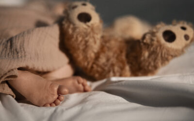 Blogfoto zindelijkheid nacht Happy Kids Boutique babyvoetjes naast knuffelbeer in bed tijdens de nacht, rustige lifestyle afbeelding over slapen en zindelijkheid bij jonge kinderen