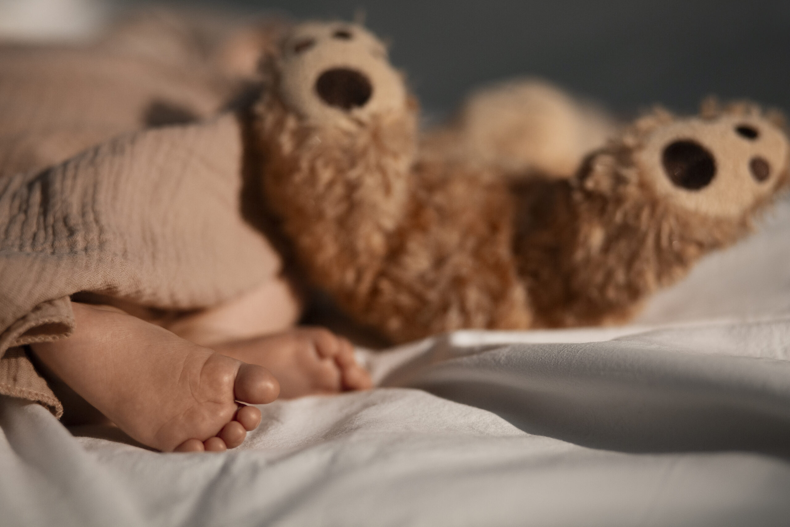 Happy Kids Boutique babyvoetjes naast knuffelbeer in bed tijdens de nacht, rustige lifestyle afbeelding over slapen en zindelijkheid bij jonge kinderen
