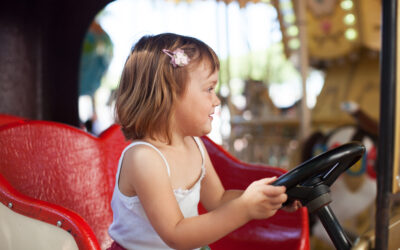 Happy Kids Boutique kind in een attractie in het pretpark, meisje zit lachend achter het stuur tijdens een dagje uit, vrolijke lifestyle afbeelding over kinderen en samen op pad gaan.