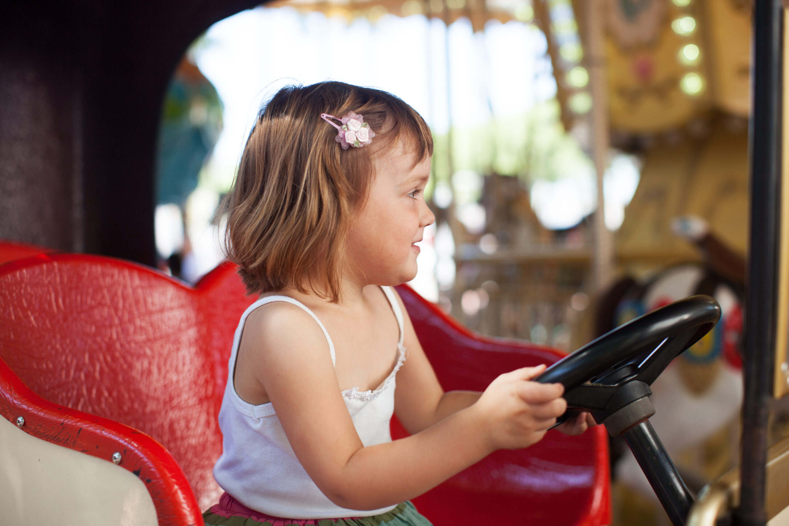Happy Kids Boutique kind in een attractie in het pretpark, meisje zit lachend achter het stuur tijdens een dagje uit, vrolijke lifestyle afbeelding over kinderen en samen op pad gaan.