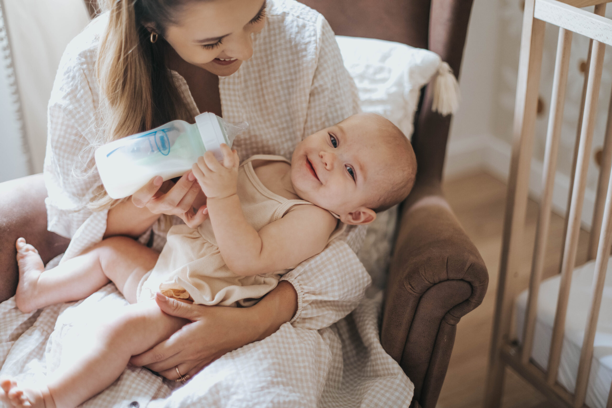 Happy Kids Boutique moeder geeft flesvoeding aan baby met Dr. Brown's babyfles, baby ligt ontspannen op schoot tijdens het voeden in een rustige babykamer