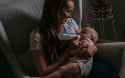 Moeder geeft haar baby ’s nachts de fles tijdens een rustig voedingsmoment.