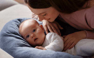 Moeder ligt liefdevol naast haar baby op een voedingskussen tijdens een rustig moment samen.