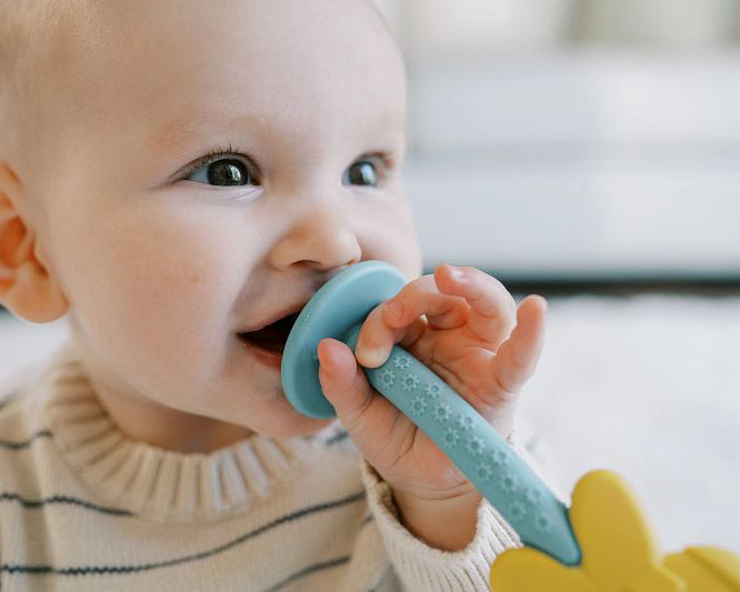 Baby bijt op blauw bijtspeelgoed en bijtring om het tandvlees te verzachten.