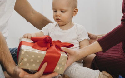 Baby krijgt van zijn ouders een ingepakt cadeautje met een grote rode strik voor Sinterklaas.